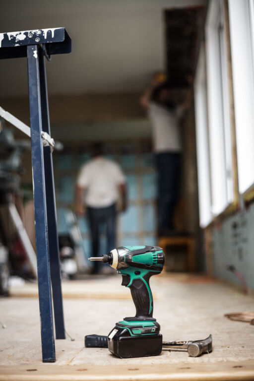 Battery Drill on the Floor with Worker in Background