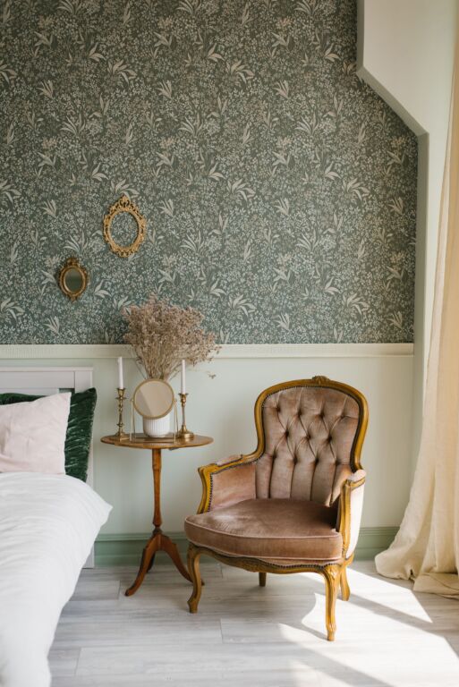 Classic bedroom interior. A brown armchair by the window and the bed and the bedside table with a mirror and candles on it